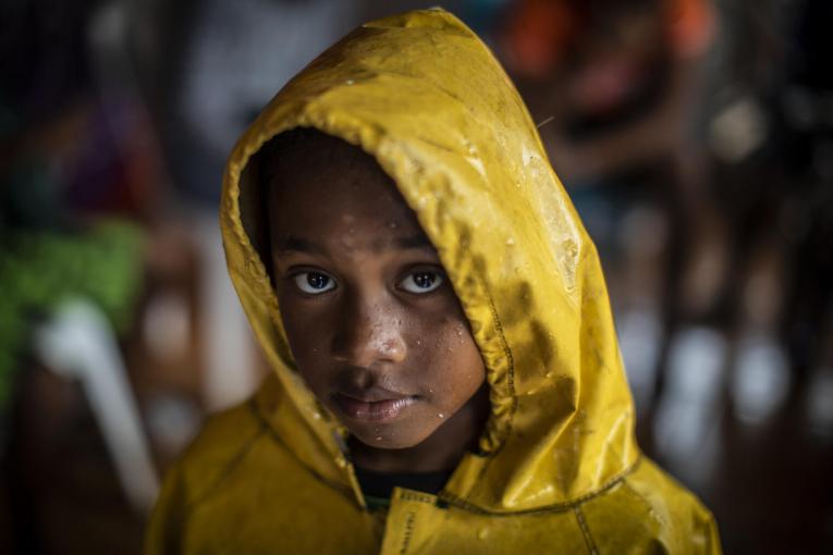 UNICEF/UN0372373/Ocon/AFP-Services A girl protects herself from the heavy rains by wearing a raincoat as she returns home from a shelter after the passage of Hurricane Iota in Nicaragua, in Bilwi, on November 16, 2020.